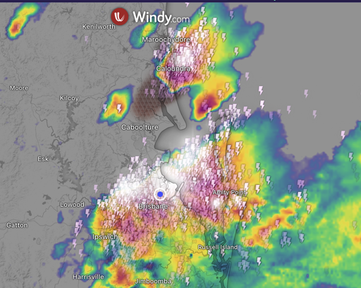 A screenshot of the weather radar around Brisbane, Australia/Meanjin.  It shows red for heavy rain, and a line of lightning bolt icons across the GPS locator mark of my current location