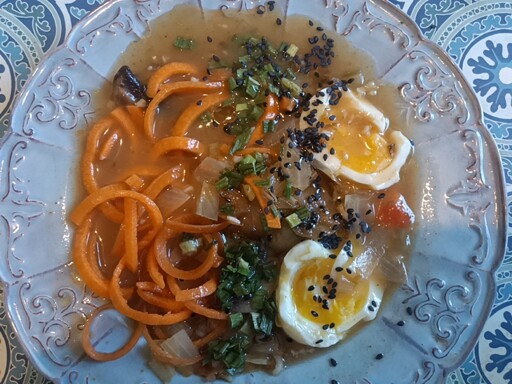 Carrot ramen, in a mushroom, chicken, onion and steel-cut oat broth, with soft-boiled egg, black sesame seeds, and toasted sesame oil.