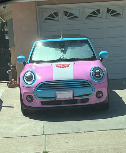An image of a car painted with the trans flag colors and with the Autobots logo on its hood 