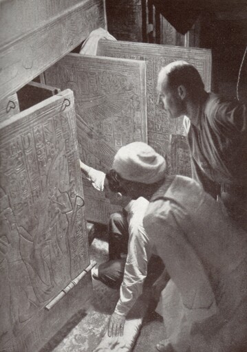 Howard Carter (squatting), Arthur Callender and an Egyptian workman, looking into the opened shrines enclosing Tutankhamun's sarcophagus